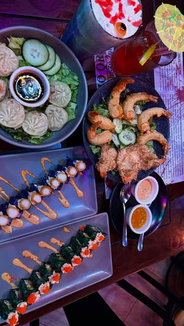 Mesa con rollos, bocadillos, ensalada y bebidas de Sushi Zú